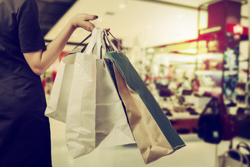 
Female hand holding shopping bags on defocused background