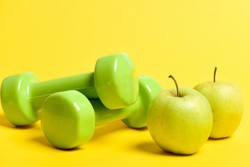 Pairs of green dumbbells and fresh apples