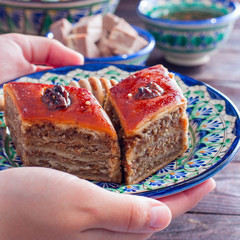Female hands serve dish with baklava, selective focus