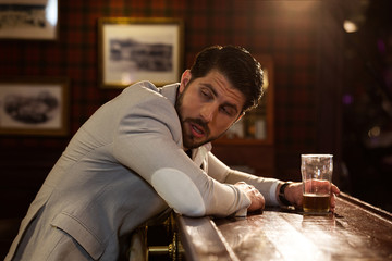 Young drunk man sitting at the counter in a pub
