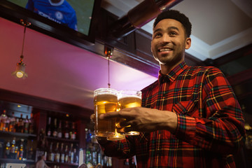 Smiling afro american man carrying glasses of beer