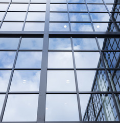 reflections of blue sky and clouds in glass facade of modern office building