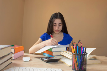 Young Girl and writing information she has found in a large book into her notebook