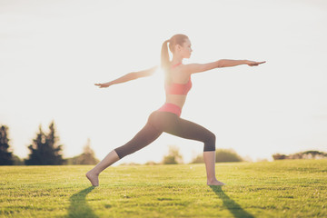 Fototapeta premium Young sport woman meditates while practicing yoga in a spring morning park. Freedom, calmness, harmony and relax, women happiness