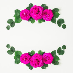 Wreath floral frame with pink roses and leaves on white background. Flat lay, top view