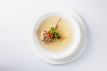 Bouillon quail egg in a white round plate on a light background (top view close)