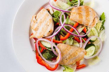 salad with chicken on a white plate on a light background (top view close)