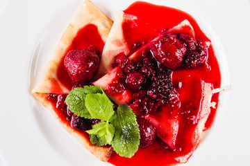 Sweet dessert. Pancakes with berry of the strawberry and raspberry sauce (top view close)