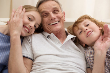 Loving positive gentleman hugging his grandchildren