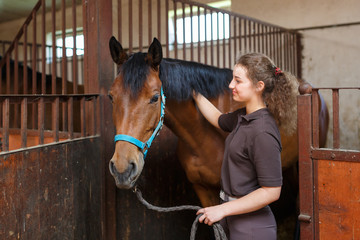 Girl with a horse in a stable