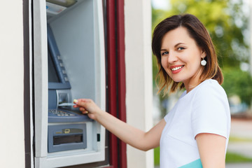 Fototapeta na wymiar Young beautiful woman using an ATM