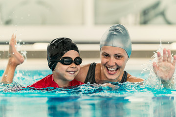 Cheerful boy with swimming instructor