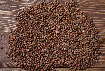 Roasted brown coffee beans on rough wooden table with blank copy space for text, top view background