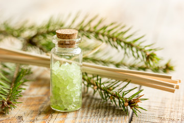 Bottles of sea salt and fir branches for aromatherapy and spa on wooden table background