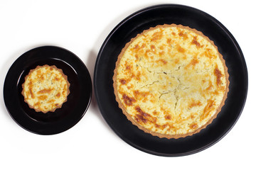 Wholemeal quiches cheese pie in white background in black plates seen from above