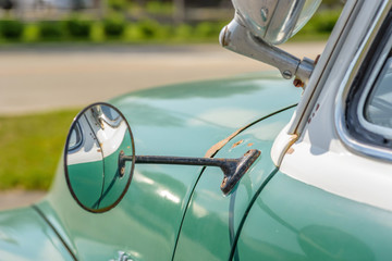 Closeup of shiny chrome rearview mirror on vintage auto © Kristen