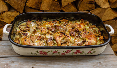 Chicken drumsticks,potatoes and mushrooms in vintage baking pan on wooden background