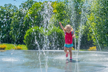 Little girl running through fountains at a splash park