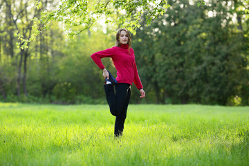 Young woman streching in green field, grass, park, morning, looking camera