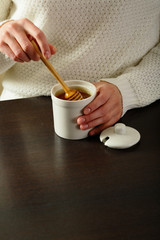 White jar with honey, in hands, spoon wooden honey