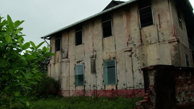 Pan across a derelict administration building on the Devils Island Penal Colony in French Guiana