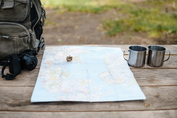 Backpack with maps and two mugs.