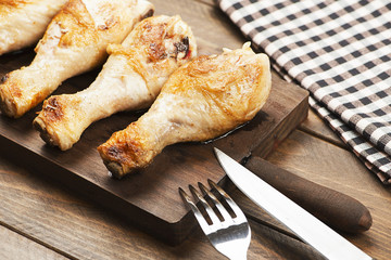Roasted chicken on board next to napkin, knife and fork.