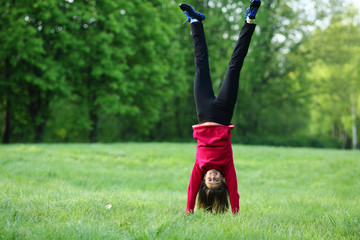 Upside down handstand happy smile sport young woman outdoor, green park, grass, full lenght