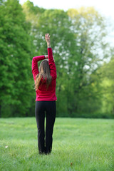 Woman stretching standing back exercise in green park, morning, sport, healthy lifestyle