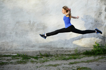 Sport bright beautiful strong woman fly jumping in twine, split on gray background