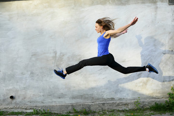 Sport bright beautiful strong woman in a jump fly jumping on gray background