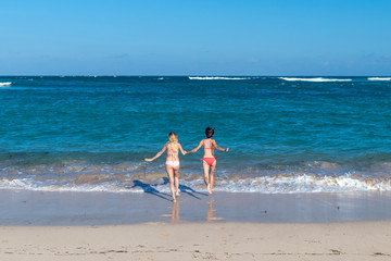 Fototapeta na wymiar Two sexy beautiful young girls running in the sea. Bali island.