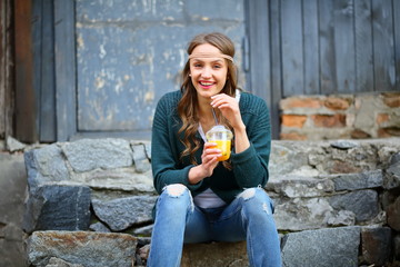 Laughing hipster girl, sitting on stone steps, holding orange juice, healthy lifestyle, fun, lifestyle