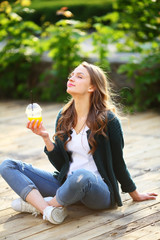 Healthy lifestyle, positive enjoying woman holding orange juice cup, healthy lifestyle, sitting cross legged in city, modern clothes, casual style, street, lifestyle, fashion, outdoor