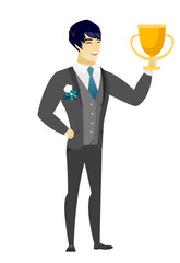 Asian groom holding a trophy.