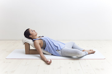 Woman in restorative yoga posture using blocks