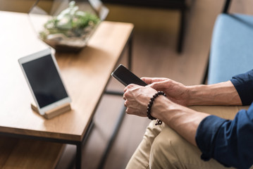 Youthful guy using mobile phone inside sitting room