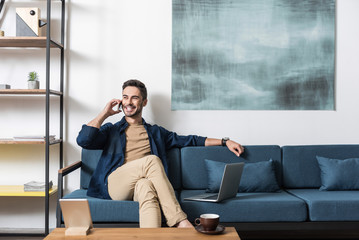 Cheery attractive guy working from home via modern technologies