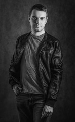 Fototapeta premium Young man in coat on dark background. Black and white toned.