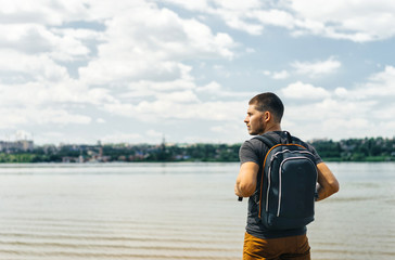 man in orange trousers with a backpack on the background of the river and the horizon. Traveling on the lung.