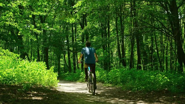 Man takes a walk in the woods on a bicycle