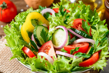 Fresh vegetable salad with greens on wooden table.