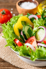 Fresh vegetable salad with greens on wooden table.