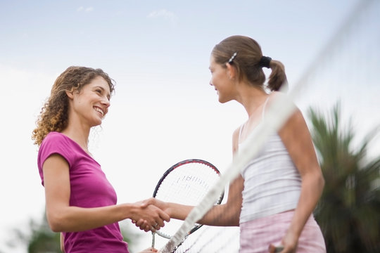 Girls shaking hands on tennis court