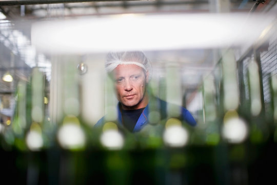Worker examining bottles in factory