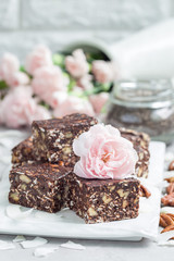 Paleo chocolate energy bars with rolled oats, pecan nuts, dates, chia seeds and coconut flakes, vertical