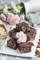 Paleo chocolate energy bars with rolled oats, pecan nuts, dates, chia seeds and coconut flakes, vertical