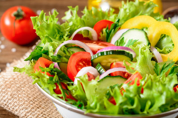 Fresh vegetable salad with greens on wooden table.