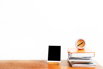 Gadget and stack of notebooks with watch on desktop