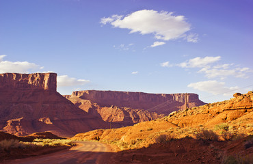 Fototapety  Castle Valley Road przez złote pustynne płaskowyże i klify o zachodzie słońca